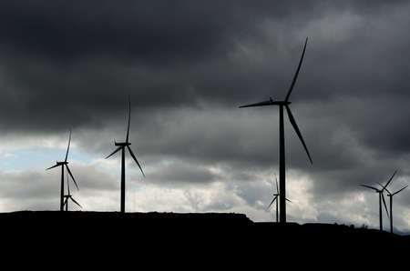 dark thunder clouds over windmills on mountain