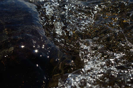 Macro photo of flowing bubbly river water on a sunny summer dayの写真素材