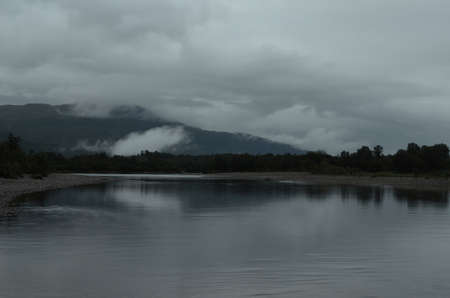 thick dark clouds over river in summerの写真素材