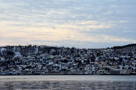 Airplane climbing over the city island of Tromsoのeditorial素材
