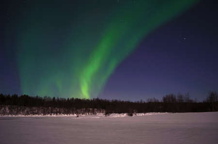 Aurora borealis on arctic winter night on a frozen snowy river bedの写真素材