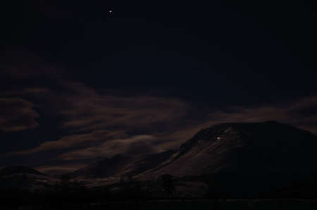 Scenic night shot of a majestic snow covered mountain surrounded by clouds in Norway