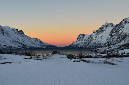 Vibrant colour on sky nover fjord with mighty mountains on each sideの写真素材