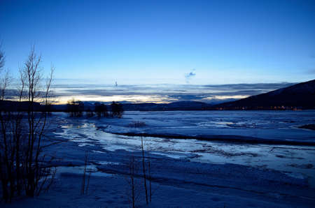 snow and ice over winter fjord with a beautiful blue dawn sky backgroundの写真素材