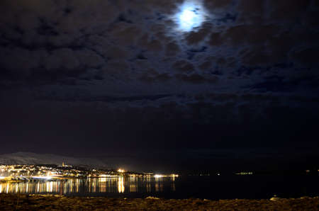 full moon behind clouds at tromsoe city island in night timeの写真素材