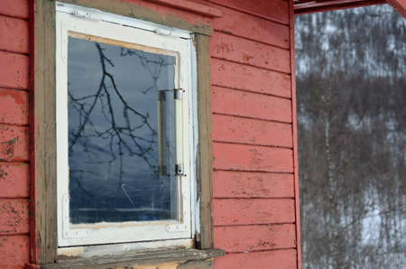 small red cabin with surroundings reflecting in glass window