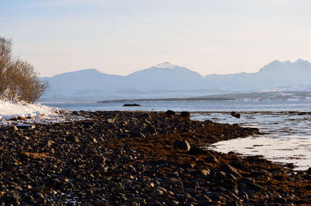 rocky seashore and mighty mountains in the backgroundの写真素材