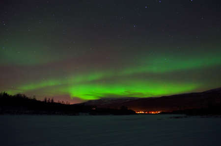 magnificent aurora borealis over frozen river bed and snowy mountain in the cold arctic circle nightの写真素材