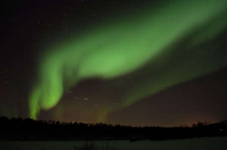 strong aurora borealis, northern light over frozen arctic circle landscape in winter nightの写真素材