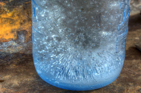 Ice bubbles in blue waterbottle on rustet metal surface