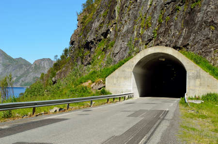 mountain tunnel opening with sea and mountain range in backgroundの写真素材