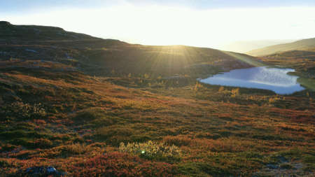 Sunshine over mountain lake and colourful autumn mountain landscape natureの素材