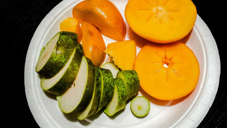 Persimon and pear fruit on white plateの素材