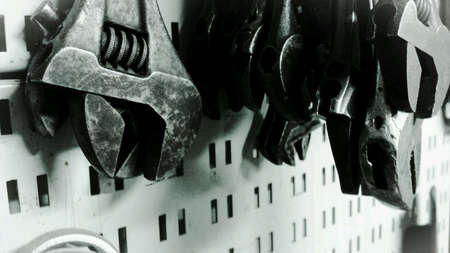Different sized metal wrenches on tool wall