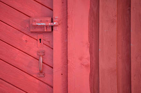 red barn door with handle and key hole and deadbolt lockの写真素材