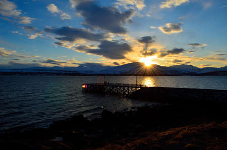 beautiful sunset over snowy mountain, fjord and pierの写真素材