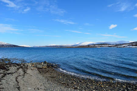 wonderful snowy mountain landscape and blue fjord in sunshineの写真素材