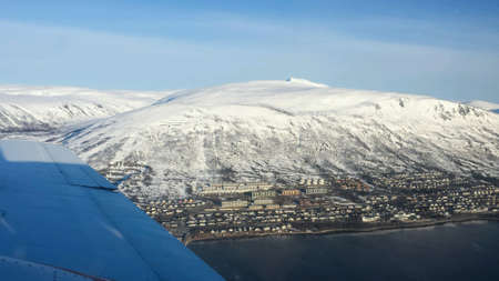 Majestic snowy mountain view in northern norway from small plane with tromsoe city in the background