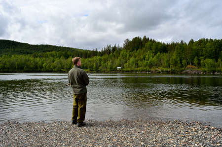 male fisherman fishing for salmon at season start in fresh water riverの写真素材