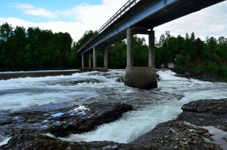 concrete bridge with massive water flow underneath in summer