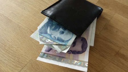 Black leather wallet with norwegian paper money on wooden tableの素材