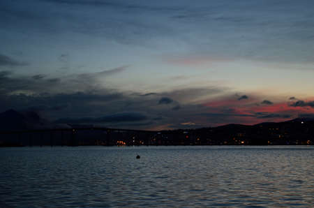 pink and colorful dawn sky over the tromsoe city island with reflection on the blue fjord surfaceのeditorial素材