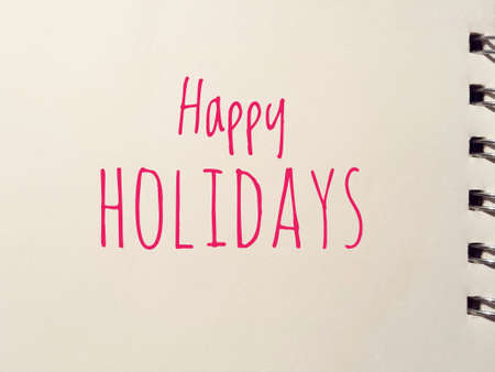 happy holidays written in red on white notepadの写真素材