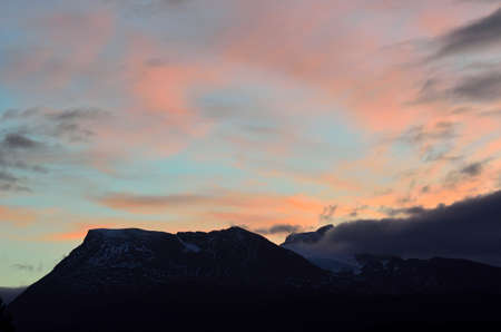 colorful sunset sky over snowy mountain in late autumnの写真素材