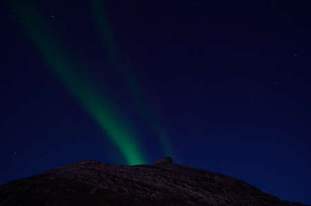 the northern light moving over mountain top at nightの写真素材