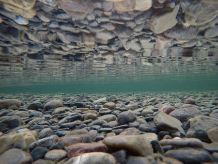 cold underwater river bed with perfect reflection on surface tensionの写真素材