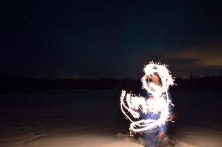 man creating shape with handheld fireworks sparkleの写真素材