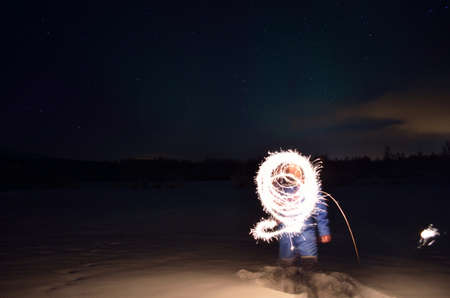man creating shape with handheld fireworks sparkleの写真素材