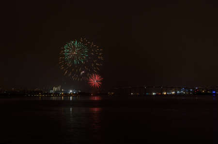 Beautiful firework on night sky in tromsoe city with bridge, cathedral and colorful reflection on...