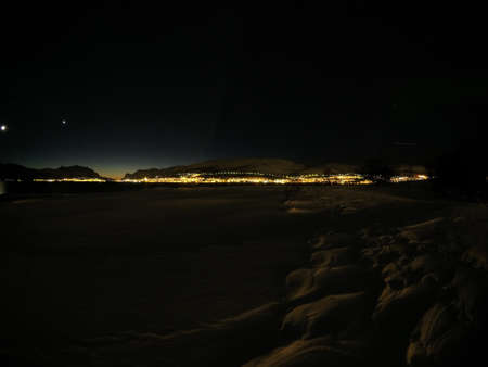 winter landscape with city lights in the background at night in the arctic circleの写真素材