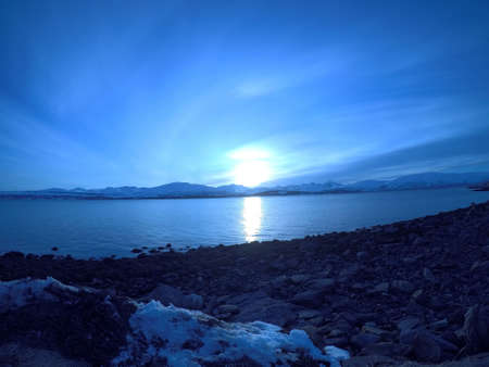 cold blue fjord and snowy mountain landscape with sunsetの写真素材
