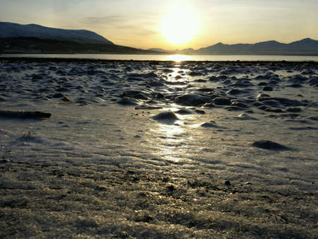 Golden sunset over frozen seashore and mountain range in the arctic circle