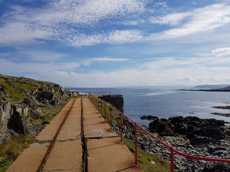 old concrete lighthouse trolley road with blue sky and ocean backdropの写真素材
