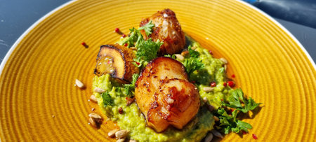 Fresh norwegian scallop on a yellow plate in summer sunshine in resturant in northern Norwayの写真素材