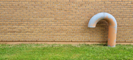 ventilation pipe on brick wall background with green grass in the frontの写真素材