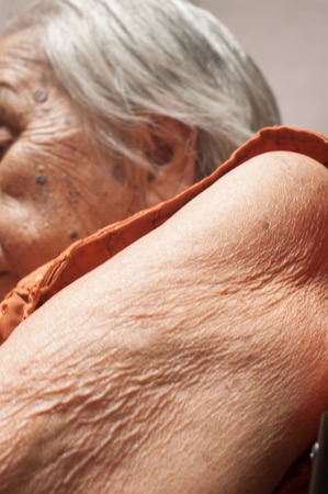 Close-up of Skin old woman on the wheel of a wheelchairの写真素材