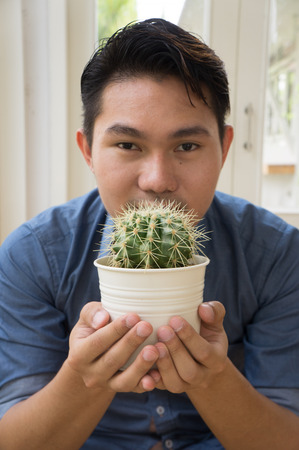 Asian man holding a pot of cactusの写真素材