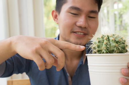 Asian man holding a pot of cactusの写真素材