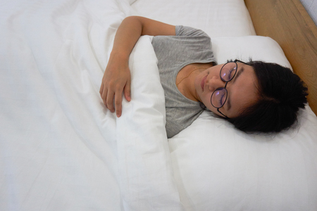 Young woman Wear glasses Relax on the bedの写真素材