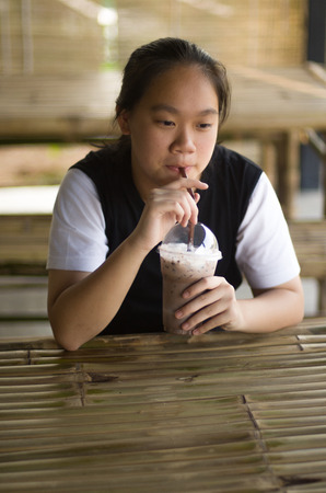 Portrait of pretty young girl smiling closeup. Young girl are drinking iced chocolateの写真素材