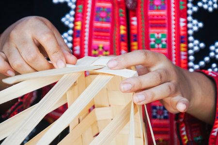 Hands of a girl wearing a tribal costume. Those hands are weaving bamboo into beautiful products.の写真素材