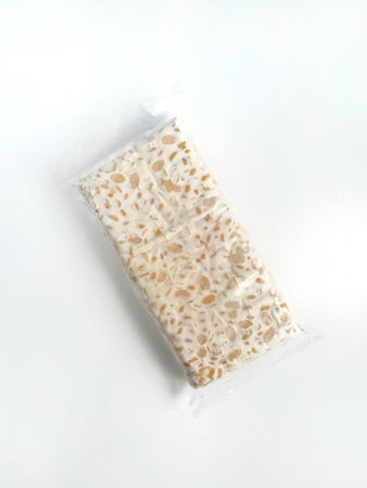 Tempe or tempeh that is fermented and covered inside plastic. Isolated on white background. Top view