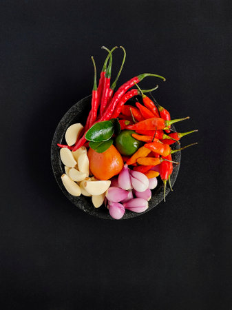 Spices ingredient in a mortar contains of garlics, shallots, tomato, lime, lime leaves, red bird's eye chilies, red curly chili peppersの写真素材