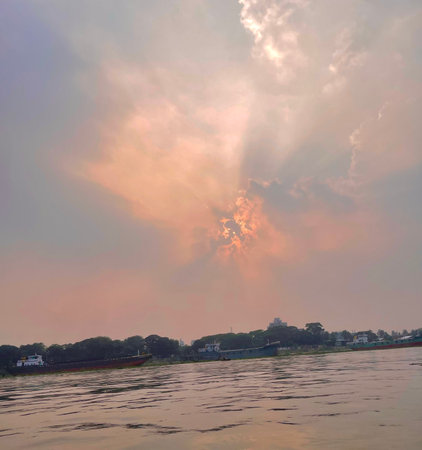 River scene with sunlight breaking through clouds at sunsetの写真素材