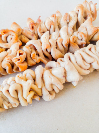 Delicious chicken intestine satay. Boiled chicken intestine satay isolated on brown background.