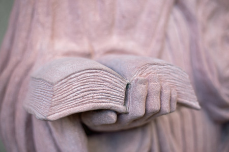 A hand holding a book, statue of stoneの写真素材